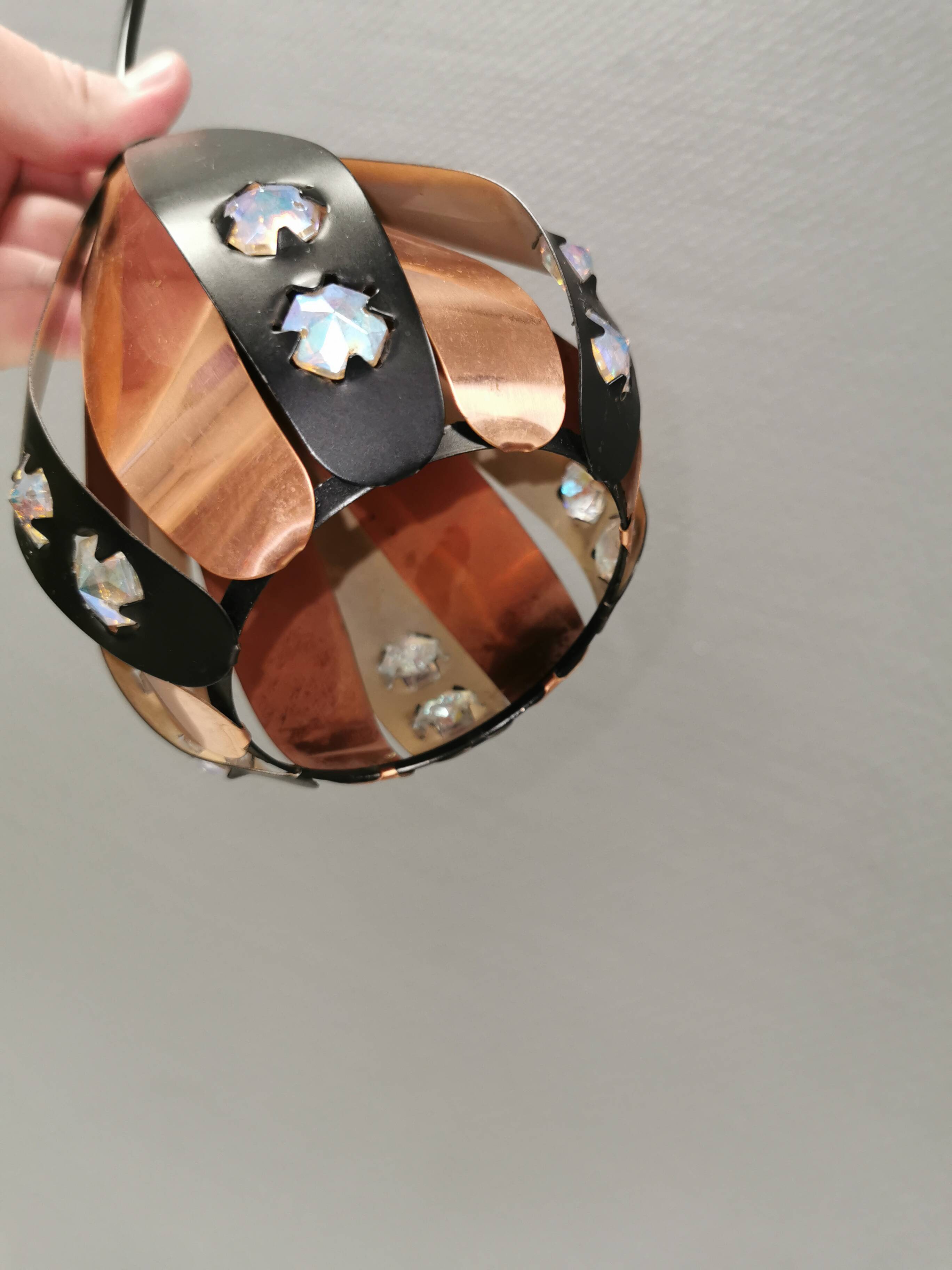 A teardrop-shaped pendant lamp made of copper, black metal, and prisms.