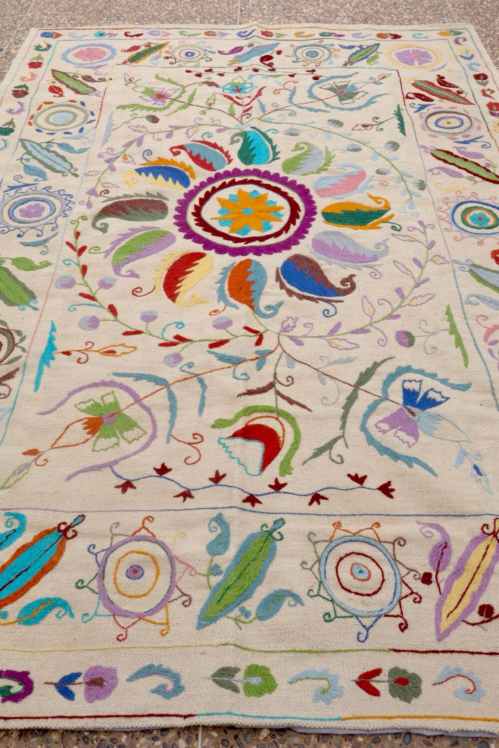 White suzani kilim rug with embroidered multi-colored patterns