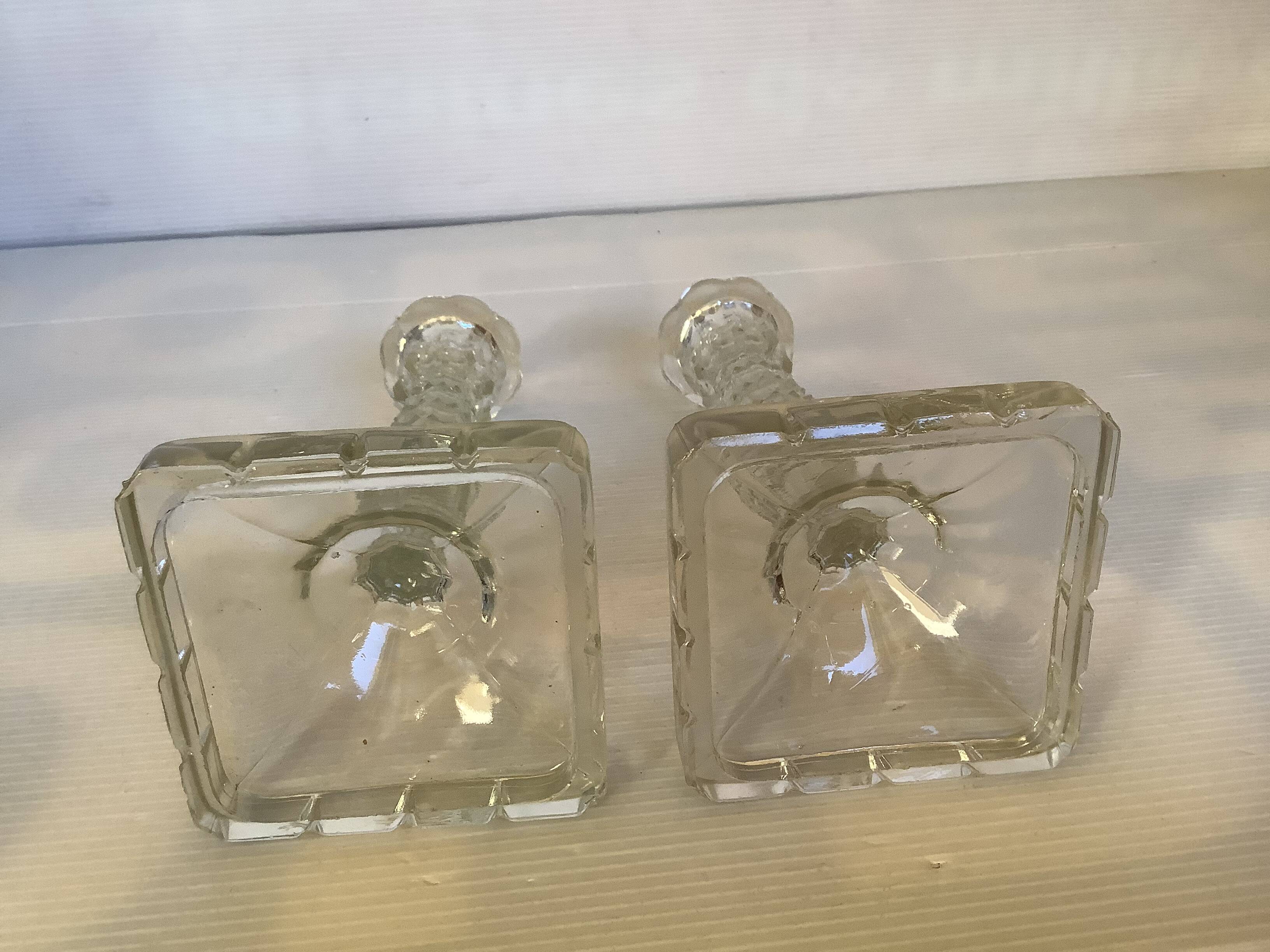 Pair of tall candle holders in the shape of a flower with a square base.