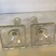 Pair of tall candle holders in the shape of a flower with a square base.