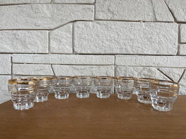 Suite of eight liqueur glasses in white glass and gold highlights. Circa 1970