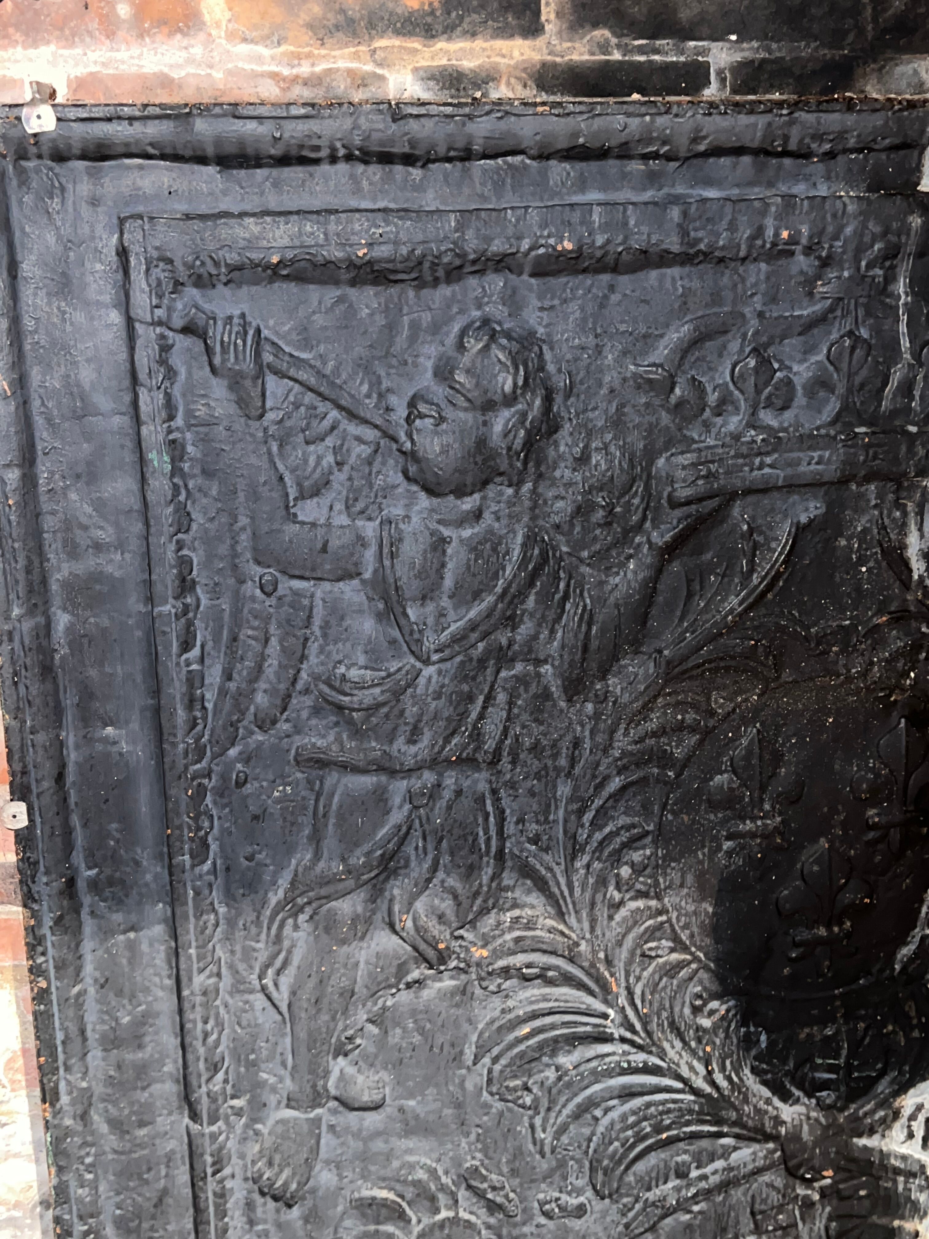 huge old fireplace plate has decoration of angels, crown and fleurs-de-lis