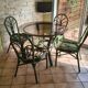 Round rattan table with glass top and 4 green rattan chairs.