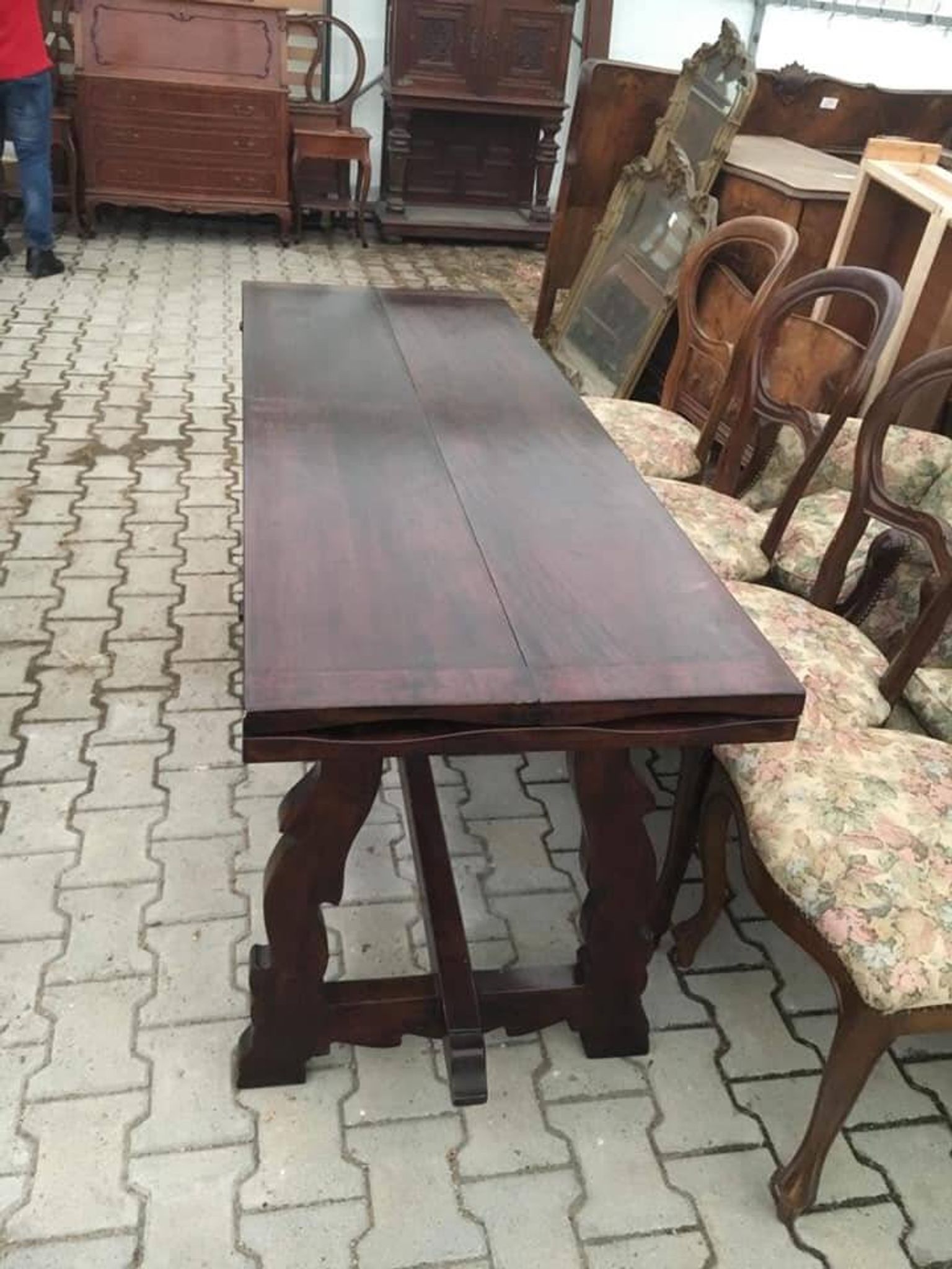 19th-century brown walnut dining table with sculpted trestle legs.