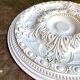 Rosette on white background, decorated with scrolls and beaded frieze ⌀ 61 cm