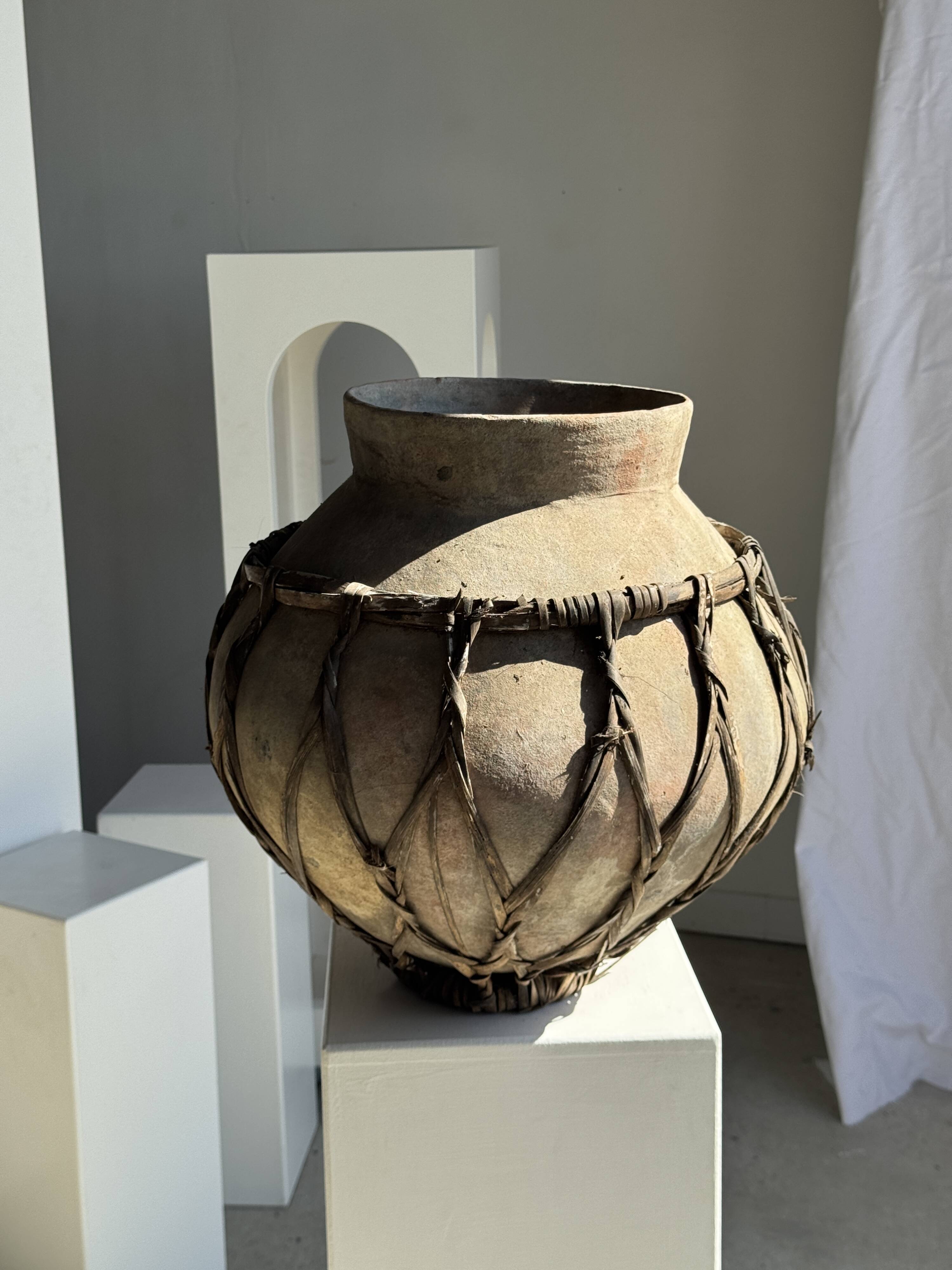 Very large light grey terracotta pot with handles and rattan crossbars.