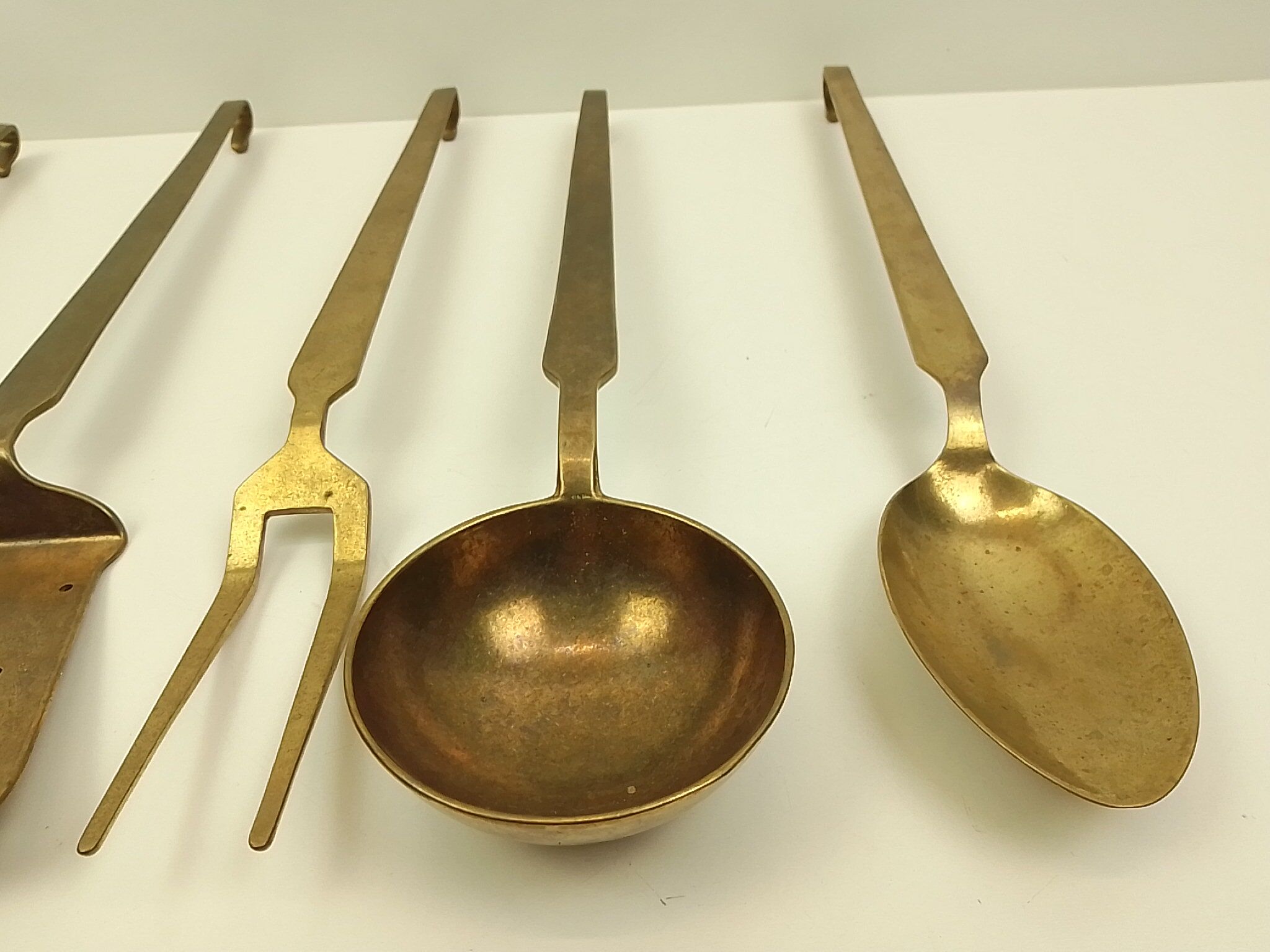 5 kitchen utensils and a brass wall mount