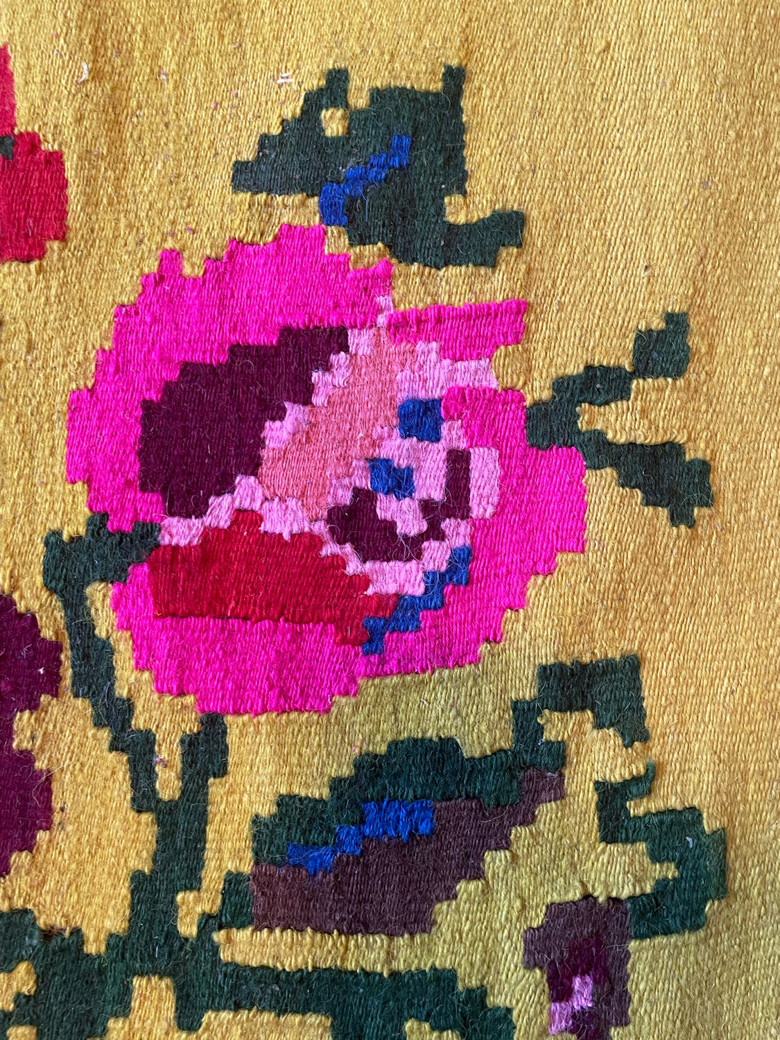 Vintage wool rug with pink flowers on green and yellow background made by hand in Transylvania