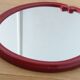 Oval mirror, red enamelled metal in Art Deco style, 49 x 39 cm.