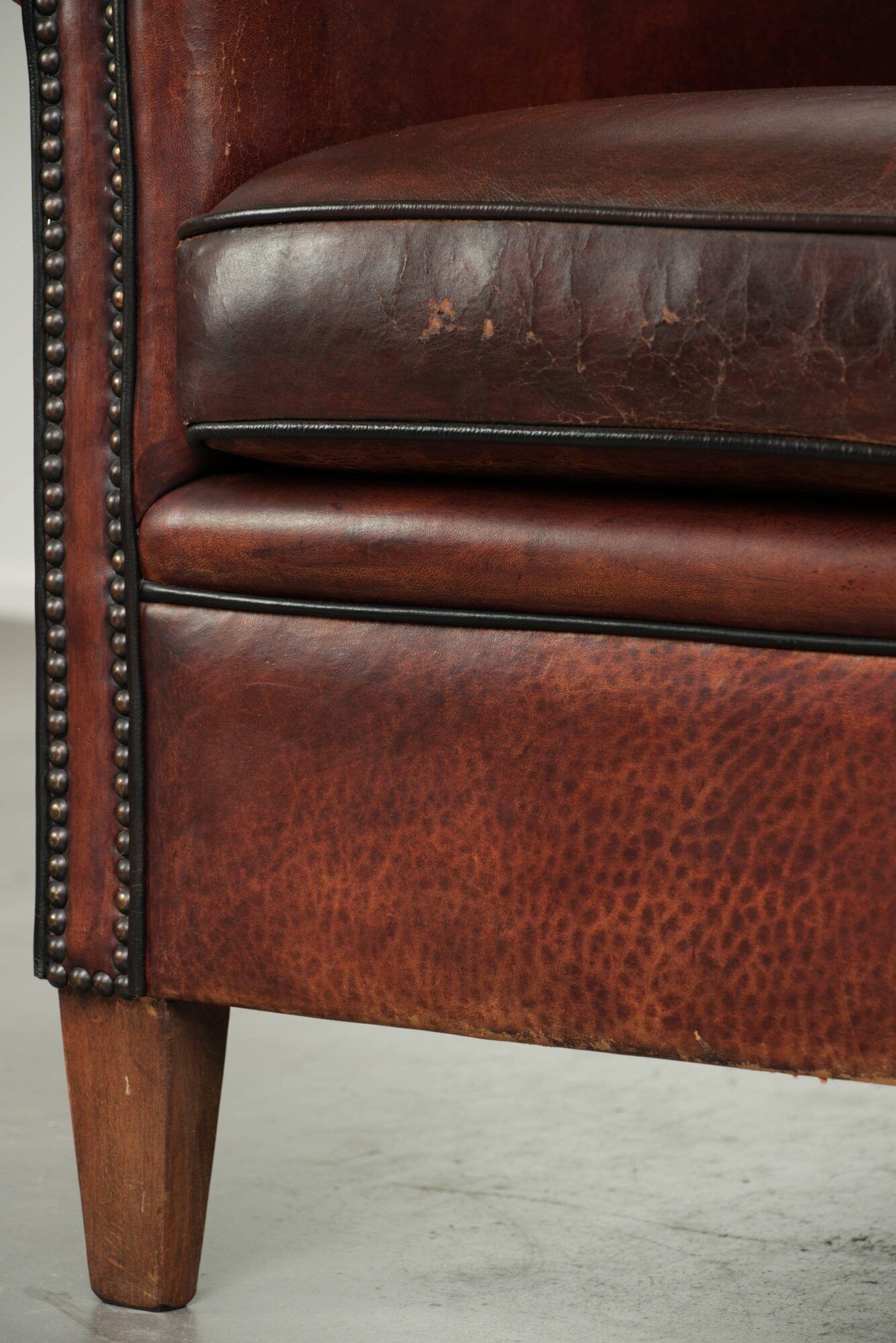 Vintage sheepskin club armchair with decorative nails and black piping