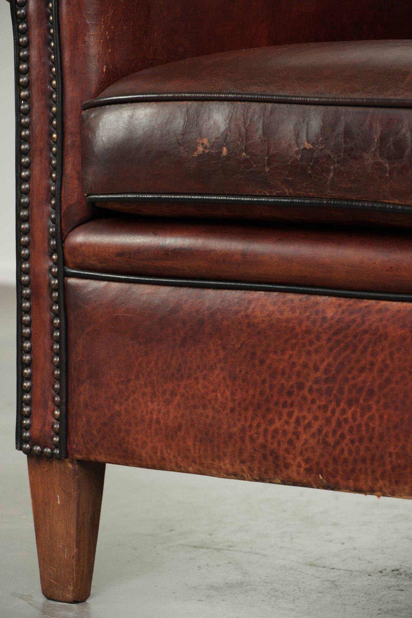 Vintage sheepskin club armchair with decorative nails and black piping