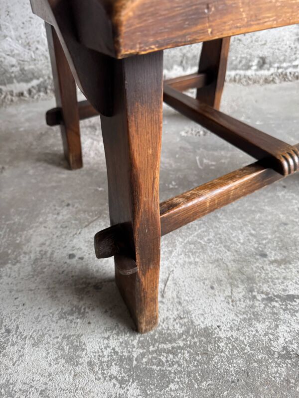 Fauteuil brutaliste en bois massif brun foncé avec assise en rotin naturel et dossier en cuir cognac