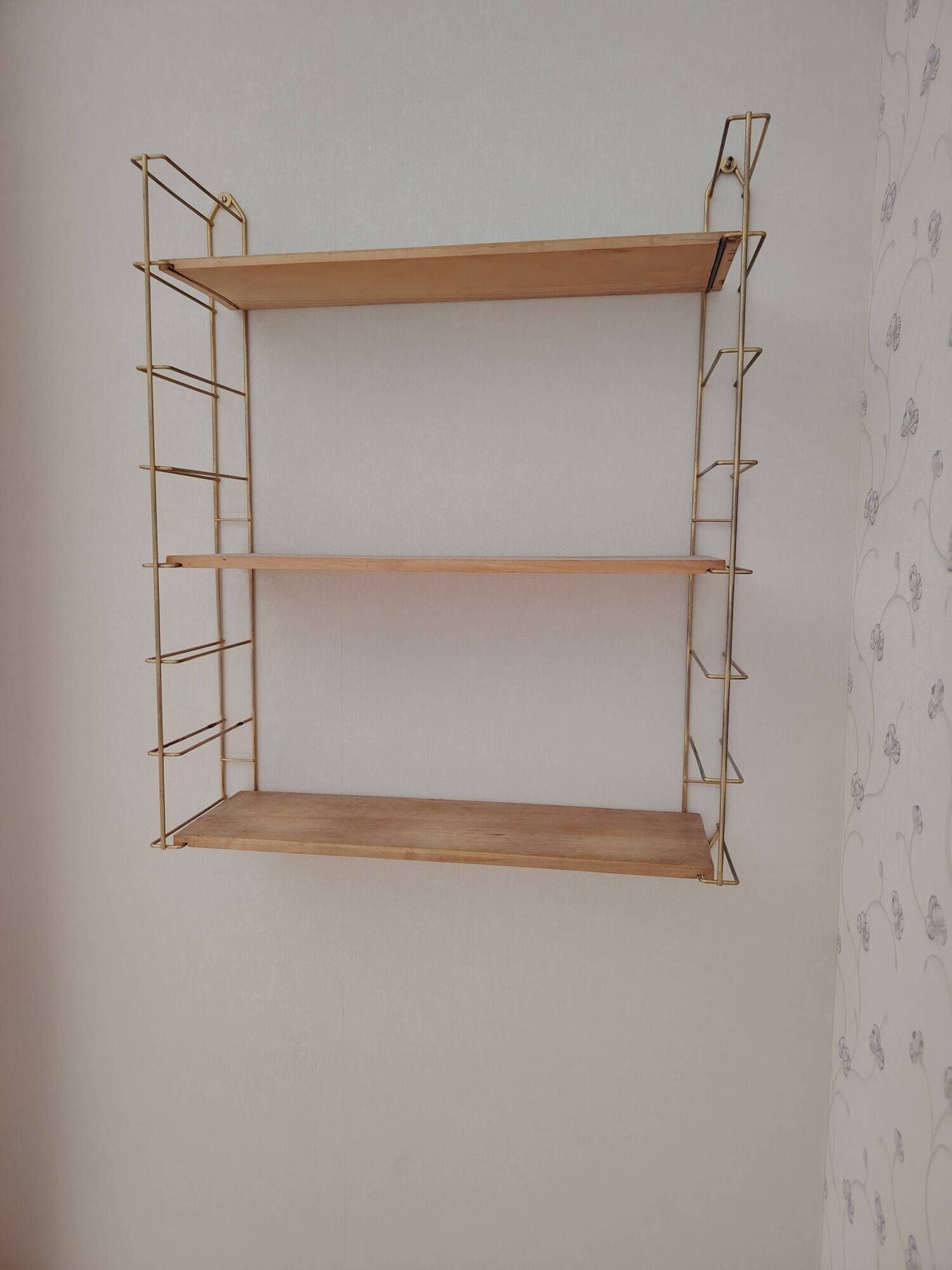 Vintage modular wall shelf in golden steel wire and wood from the 1950s.