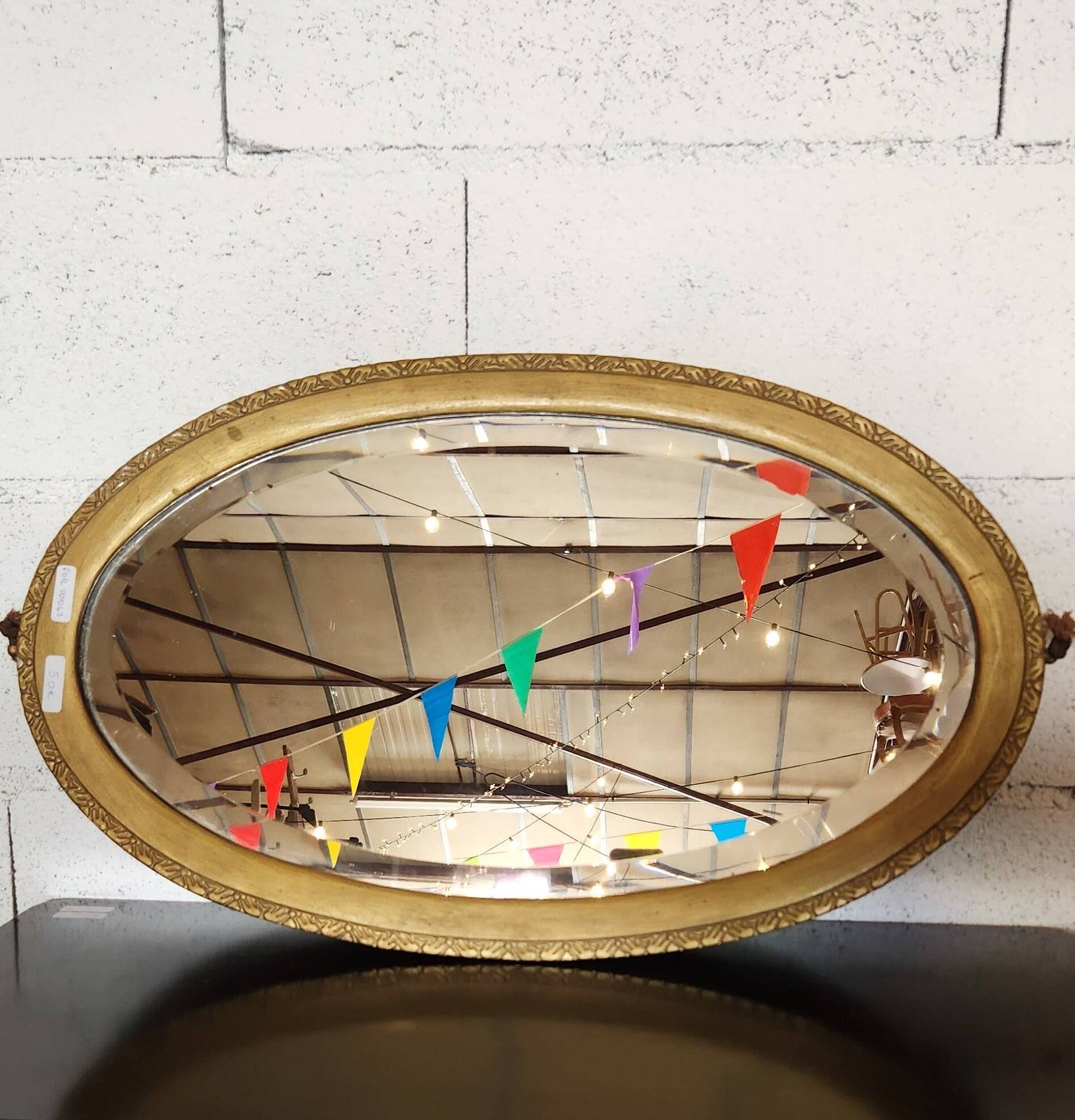 Antique oval mirror with a gilded frame, bevelled glass.