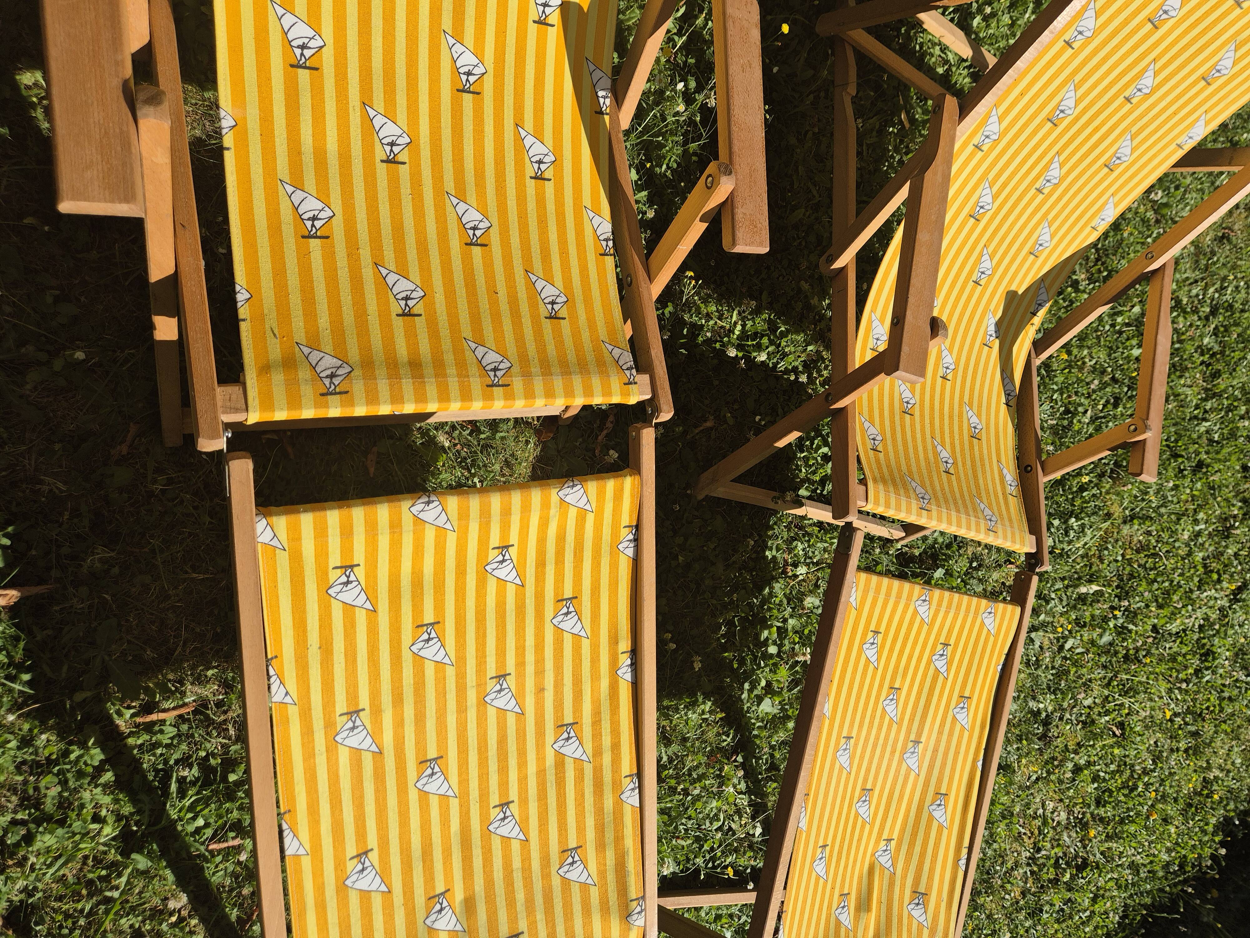 2 vintage Chilean deck chairs made of wood and yellow fabric printed with sailboats, with footrests.