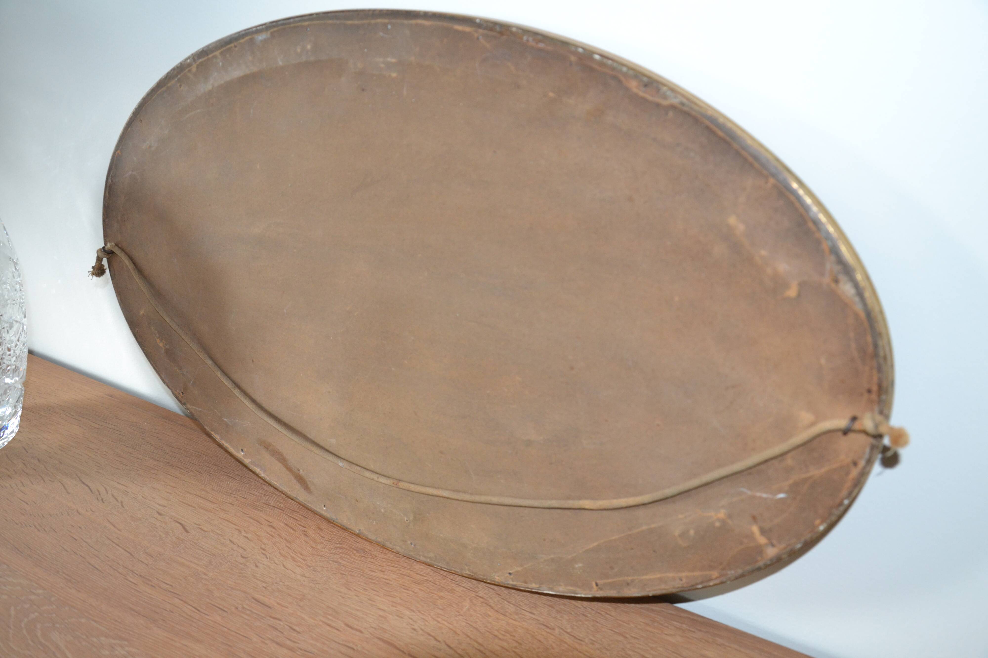 Old oval beveled wooden mirror, partly gilded and carved
