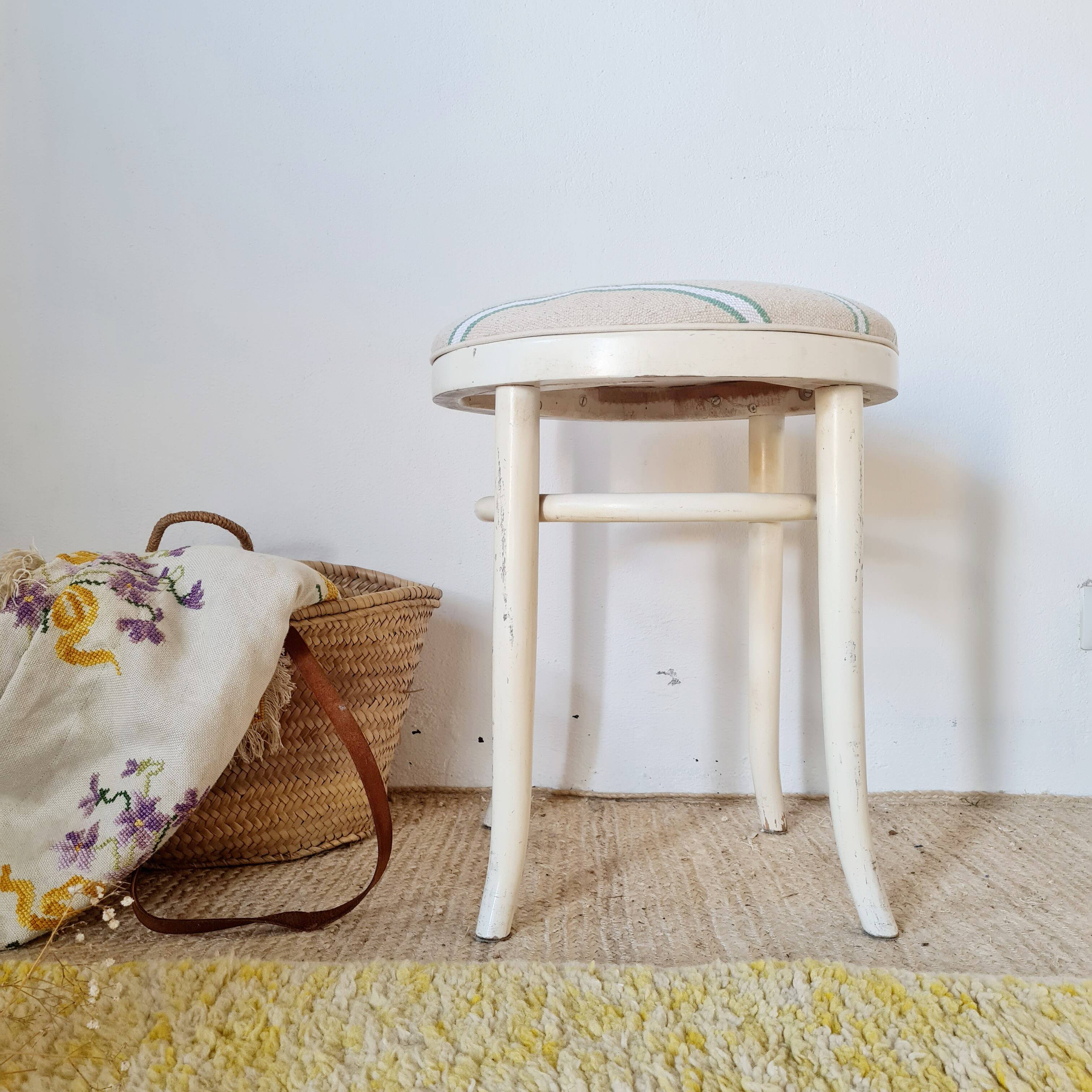 Antique stool with a wooden frame and a cream and green striped fabric seat.