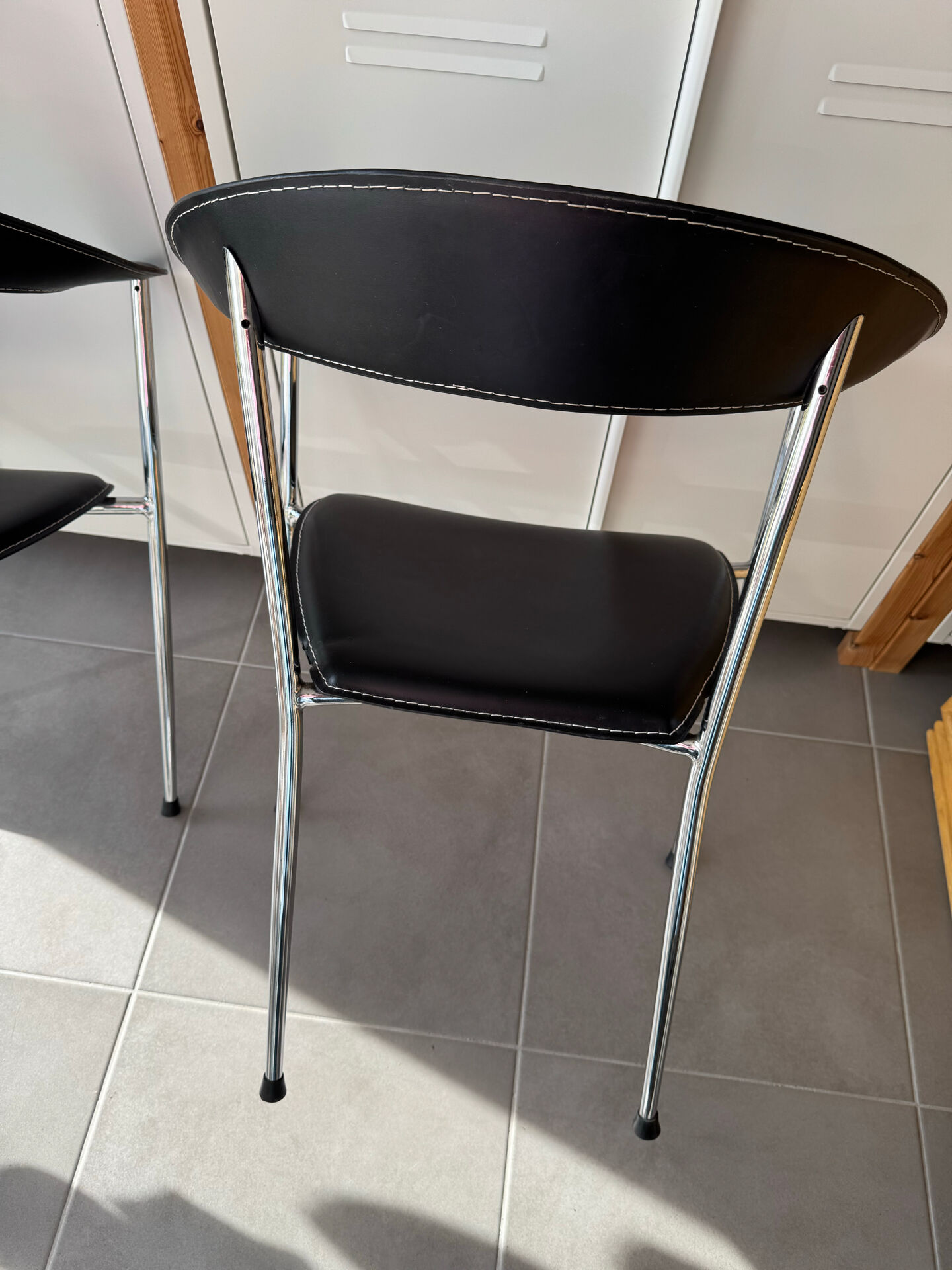 Set of two metal chairs with a brushed finish and black leather.