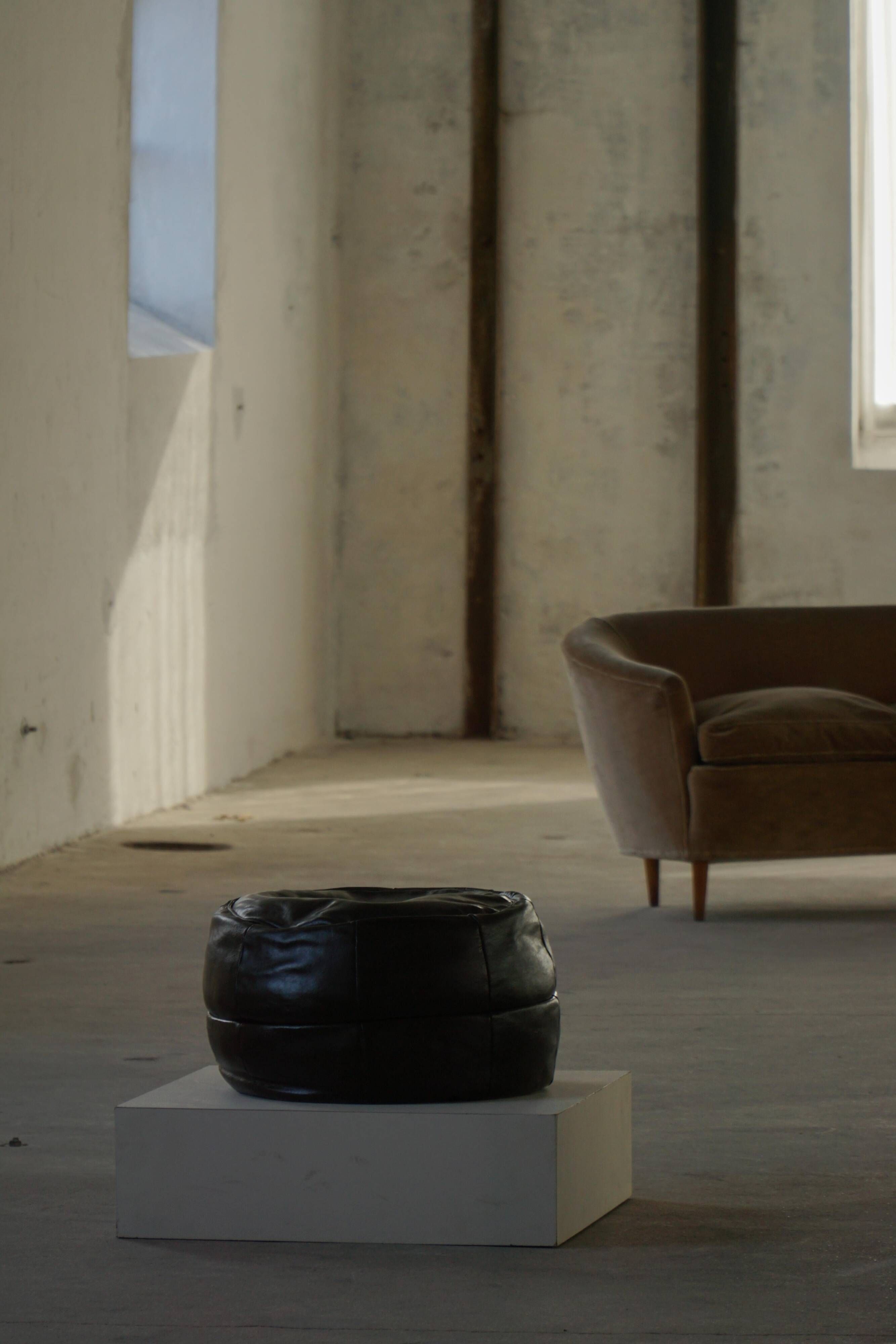 Vintage black leather pouf/ottoman with a rounded shape, French mid 20th Century.