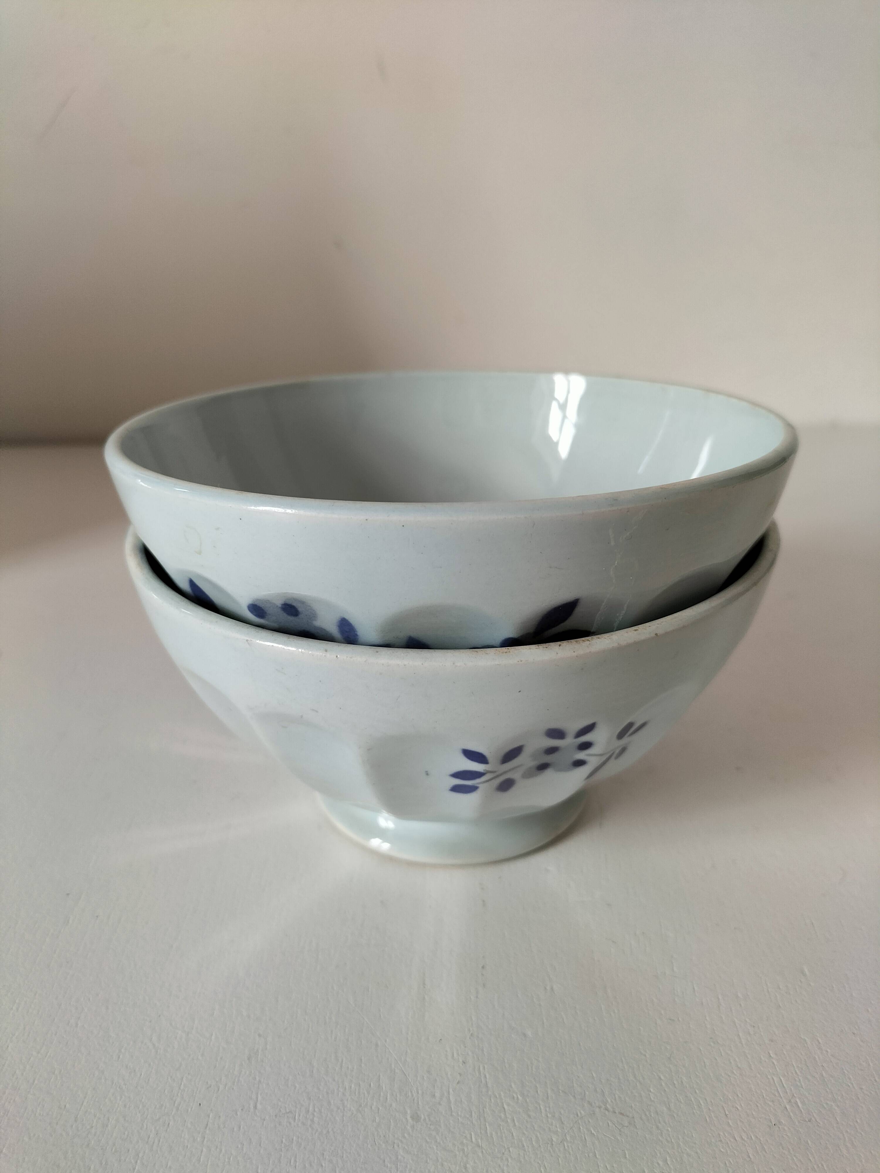 Two vintage farm bowls on a pale blue pedestal with floral decoration.