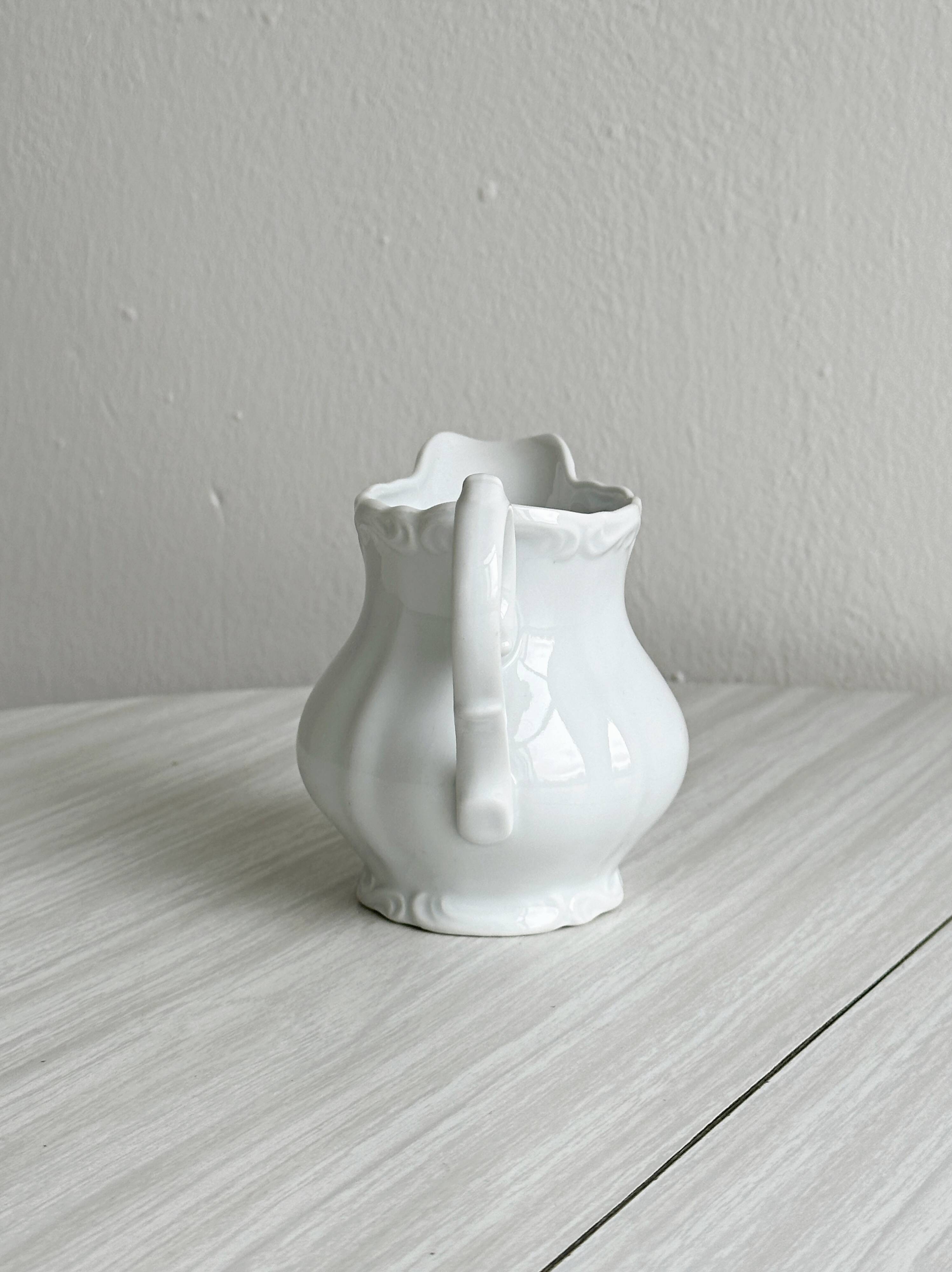 Old white porcelain milk jug, cream jug with relief.