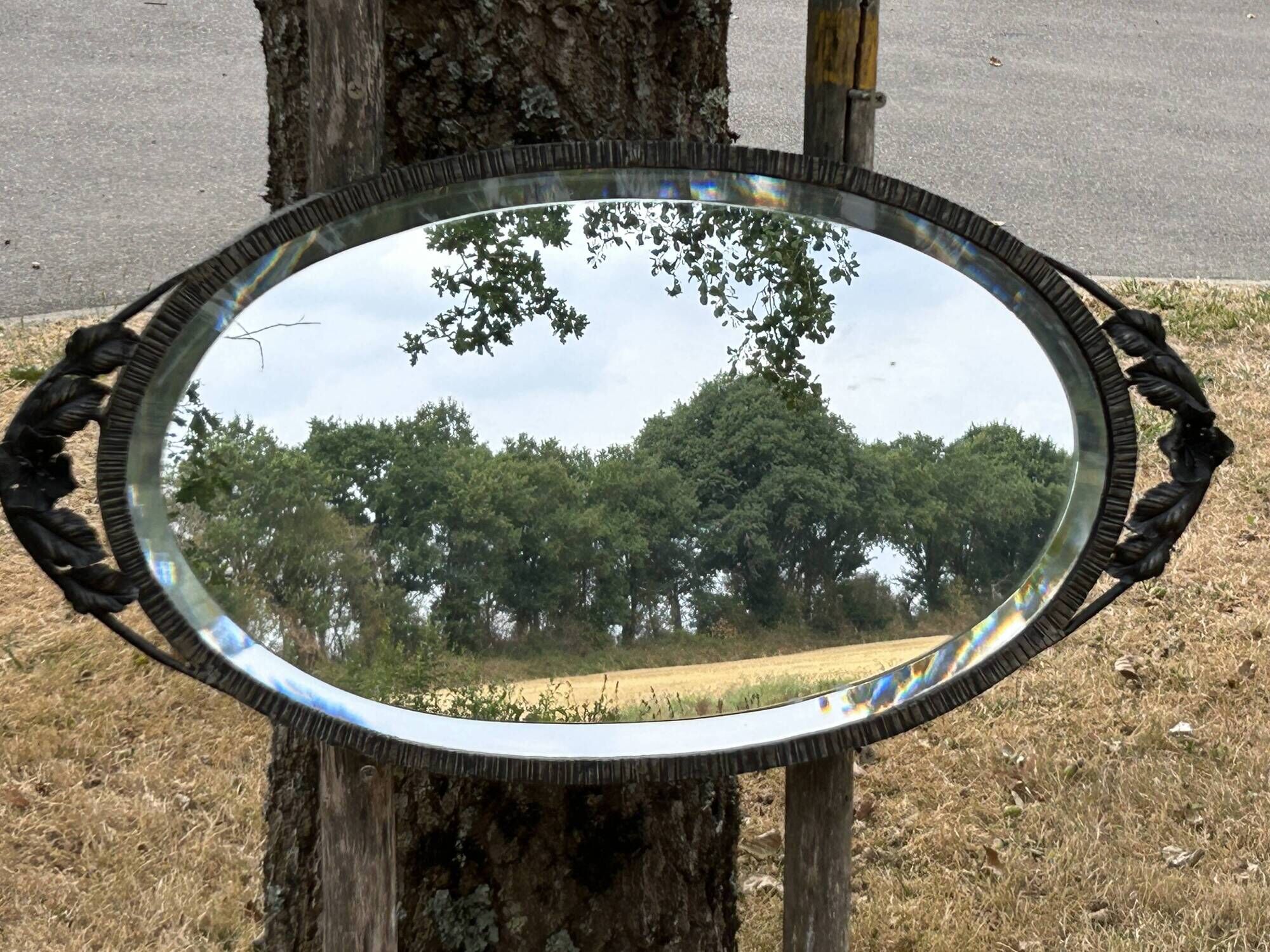 Bevelled oval mirror, richly crafted Art Deco wrought iron.