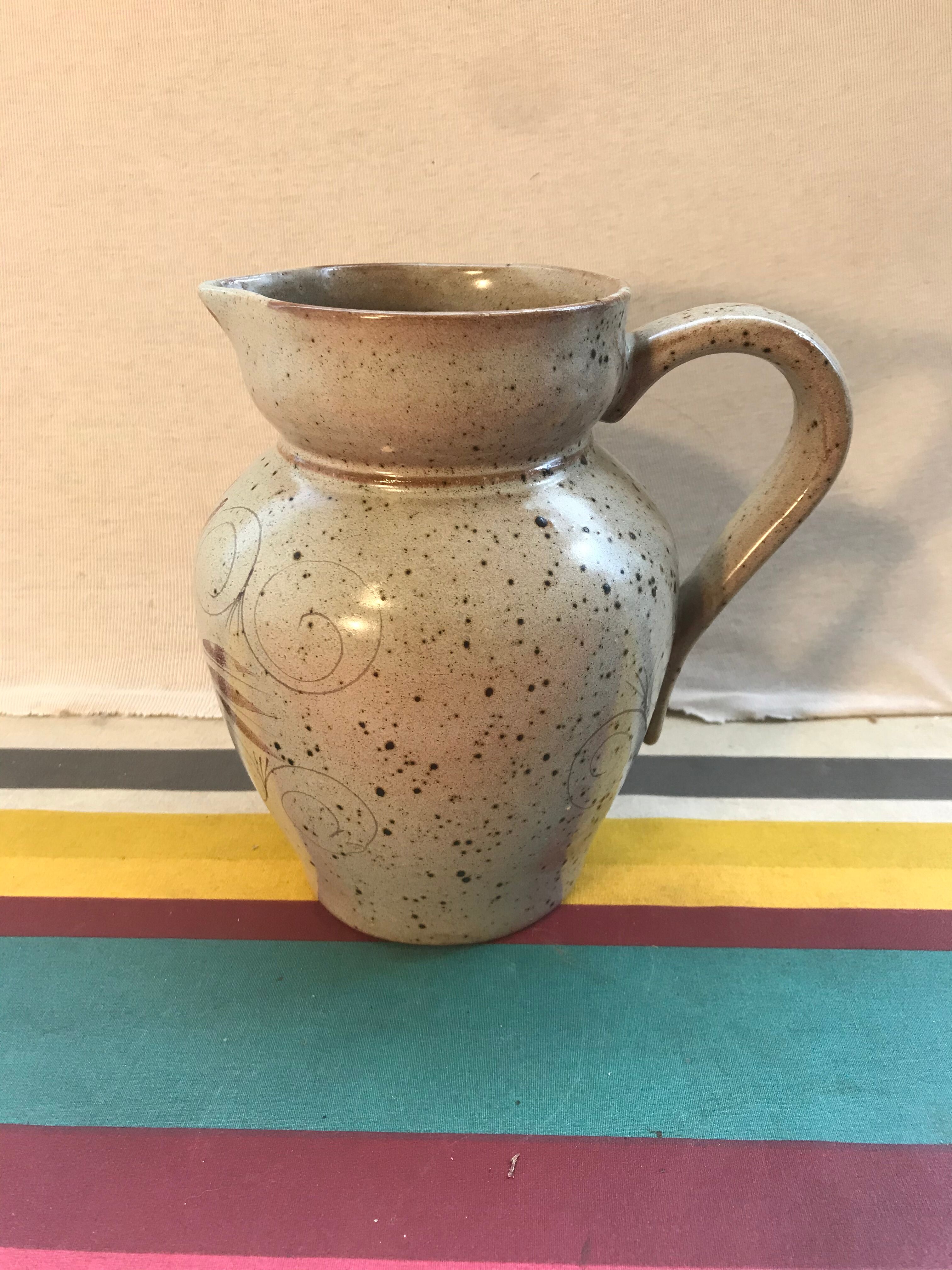 Old gray pitcher with black drawings and vintage stamped handle