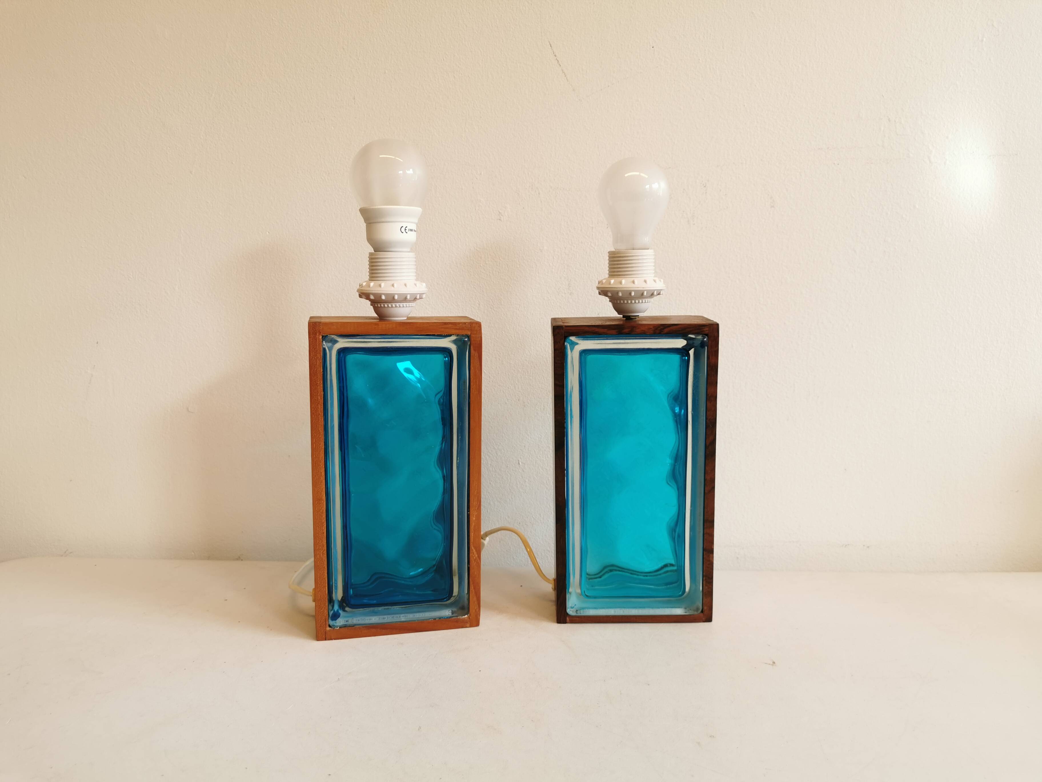 Two Swedish table lamps in solid pressed blue glass and teak wood "frame".