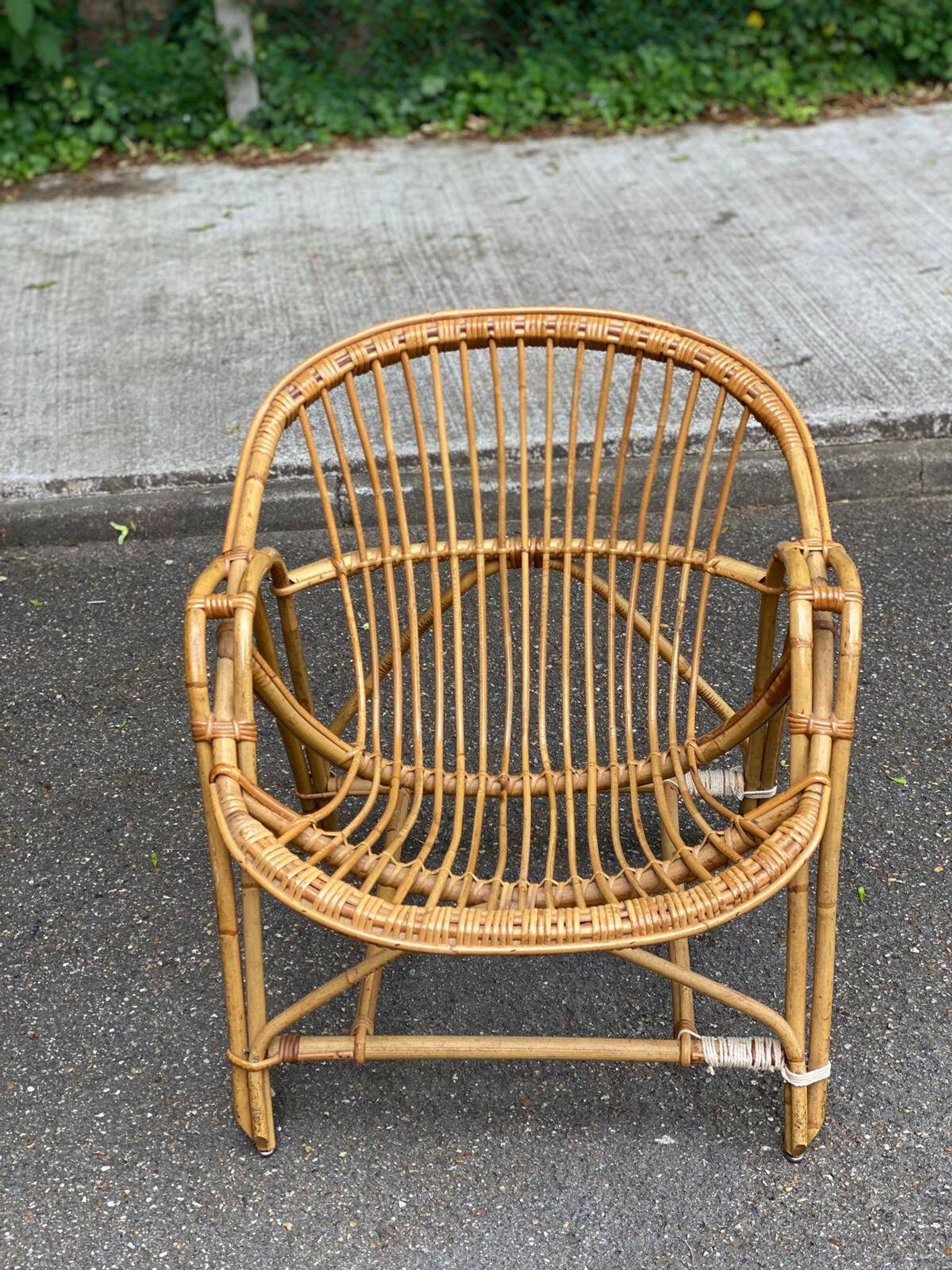 1970s adult rattan and wicker armchair with a round burgundy velvet cushion.