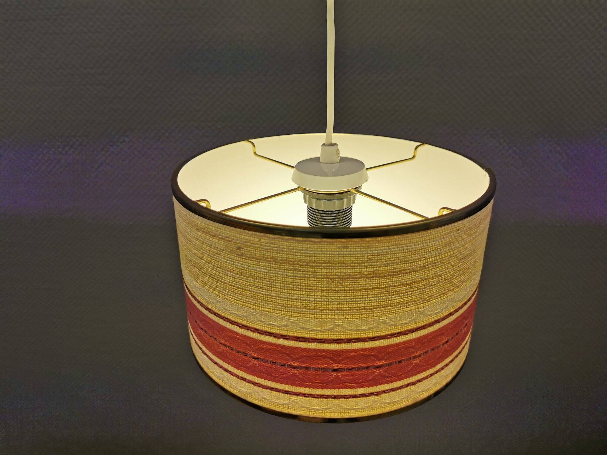 Hanging lamp with brass-coloured details, made of fabric with intact plastic bottom grille.