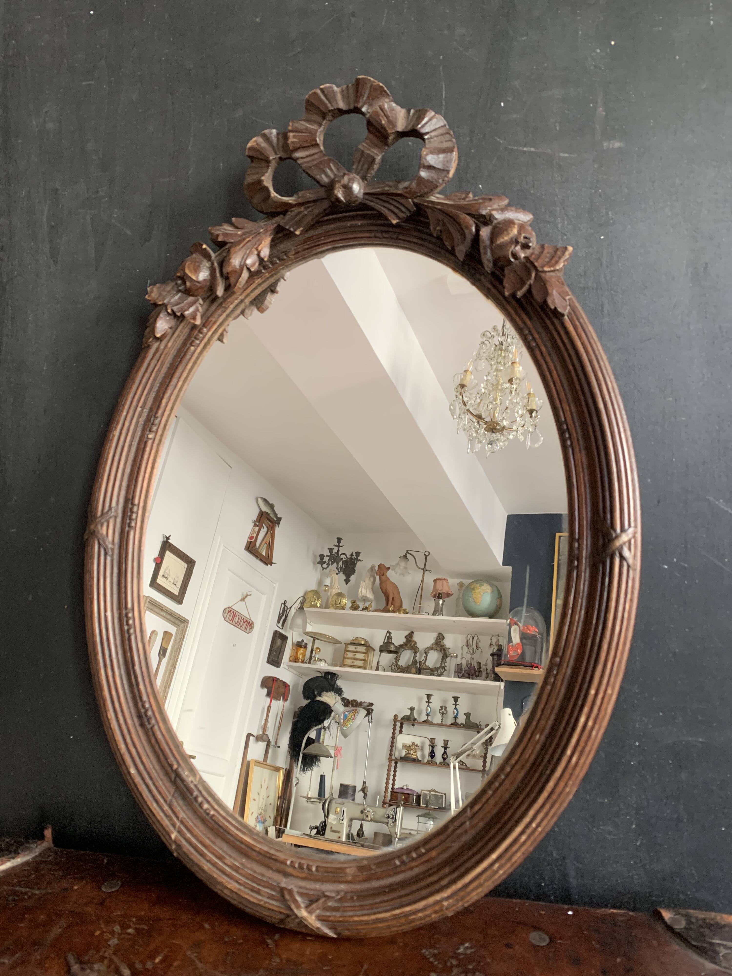 Antique oval mirror in carved wood and Louis XVI style knot