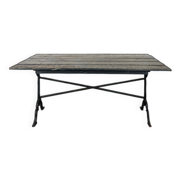 Garden table with a cast iron base and a green painted wooden top.