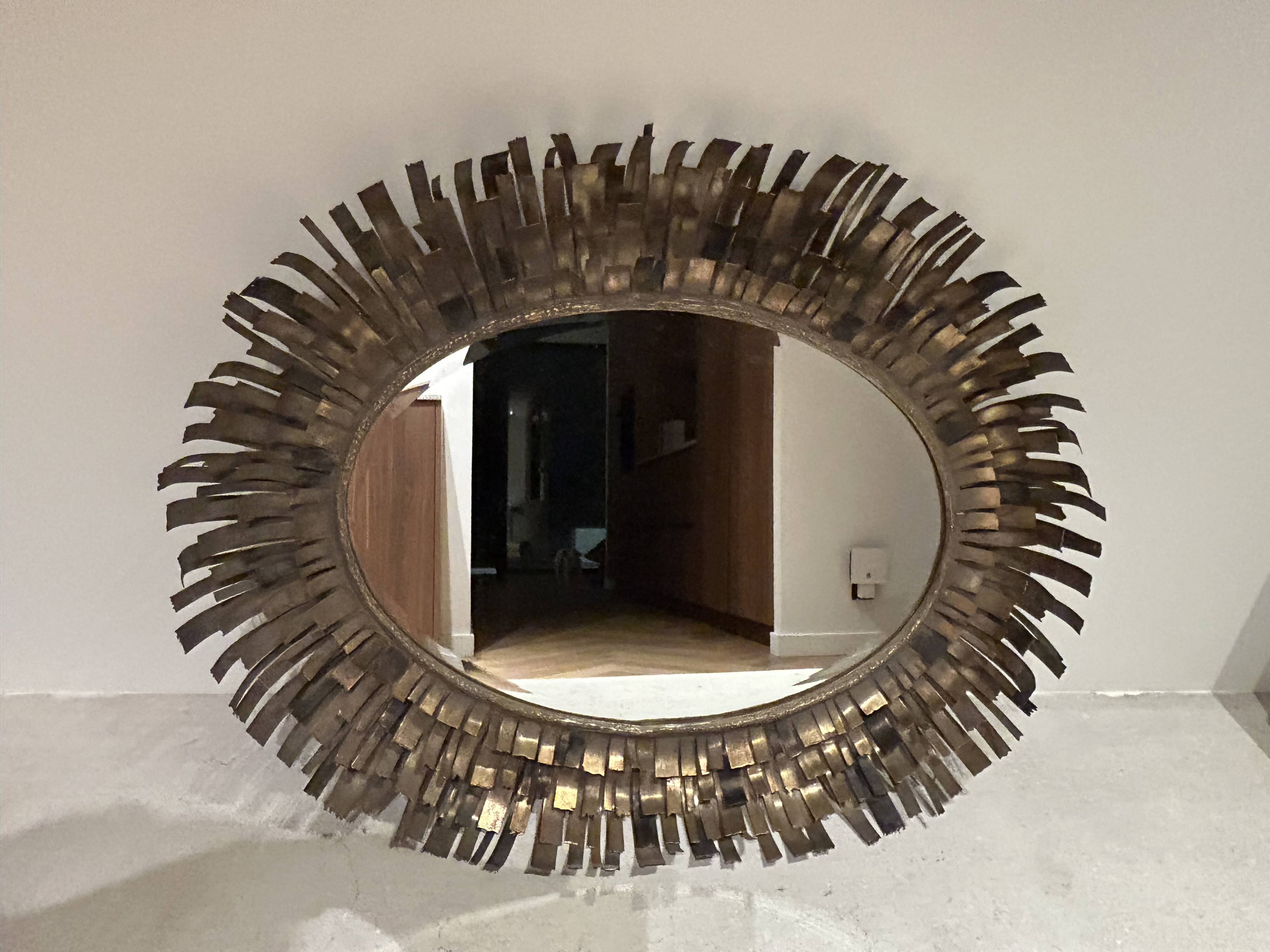 Large oval sun mirror in patinated gold metal.