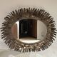 Large oval sun mirror in patinated gold metal.