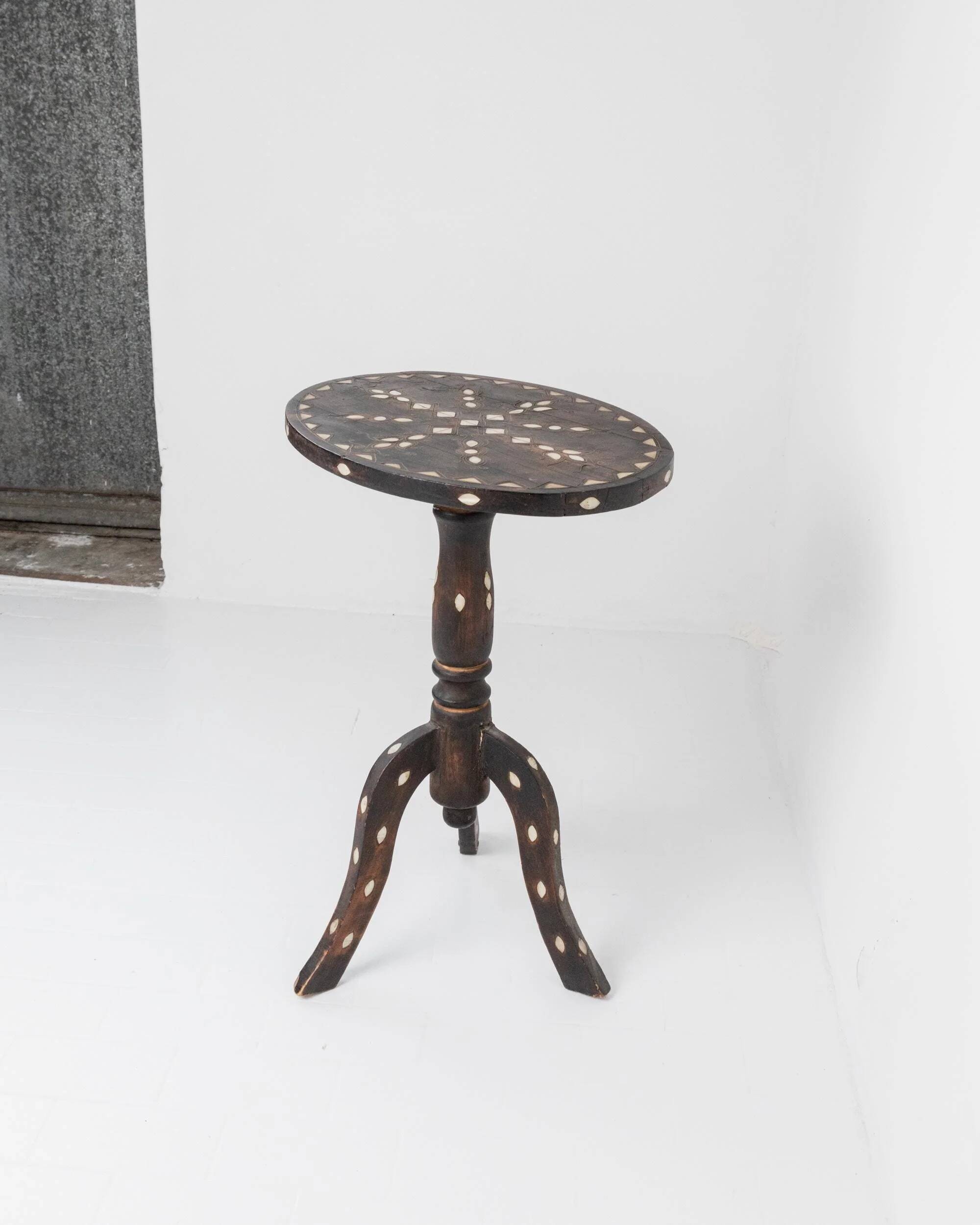 Vintage side table from the early 19th century, dark wood with mother-of-pearl inlays, oval shape with three legs, ethnic style.