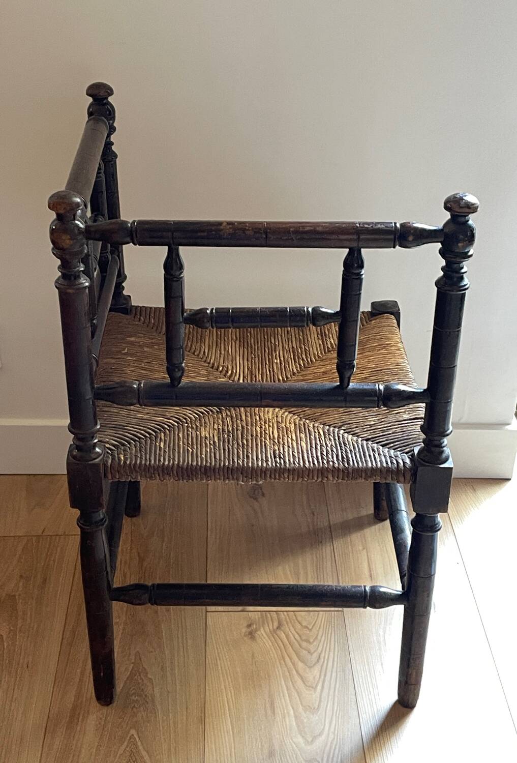 Corner chair made of turned wood with a straw seat.