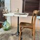 Bistro table with a raw wood top and a central cast iron base.