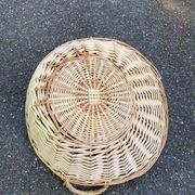 Round presentation basket made of woven wicker and rattan.