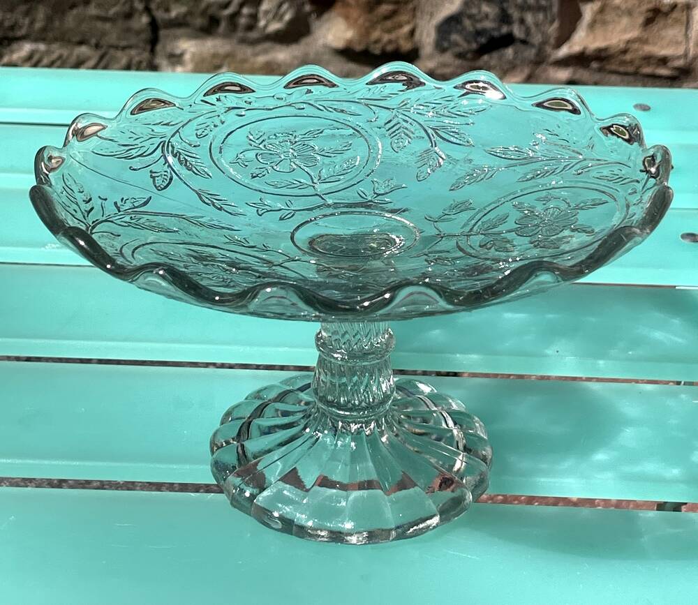 Footed bowl or pressed glass compote with floral decoration for table decor.