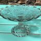 Footed bowl or pressed glass compote with floral decoration for table decor.