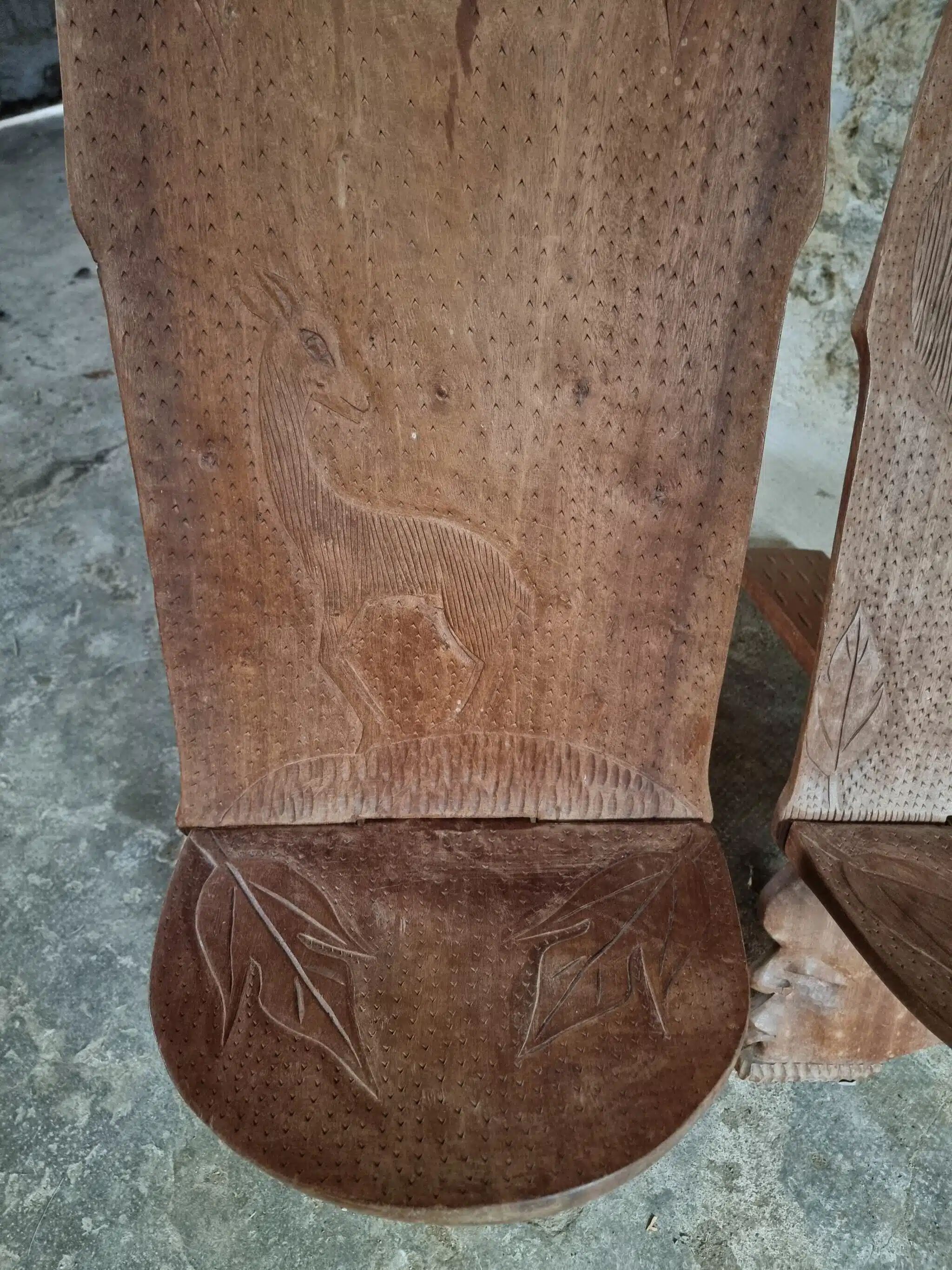 Pair of hand-carved wooden folding chairs – African origin, animal and face motifs, mid-20th century