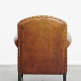 Sheepskin leather armchair in a cognac color with black piping