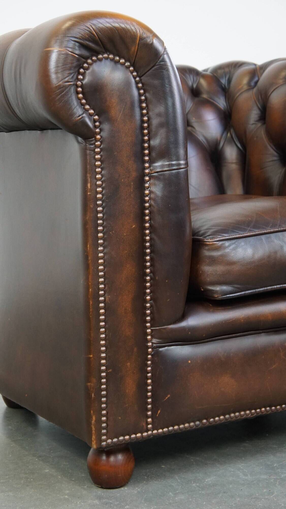 Cowhide English Chesterfield armchair with ball legs and timeless finish