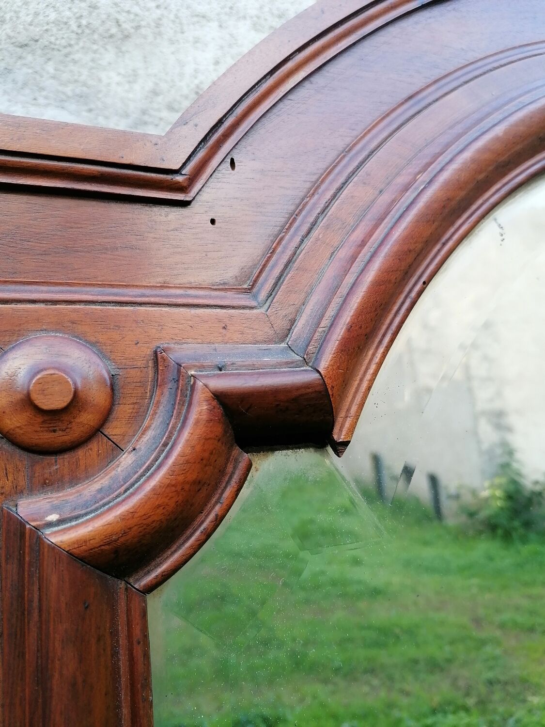 Old beveled solid wood mirror of a cabinet door.