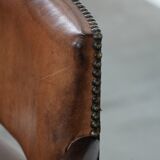 Elegant antique sheepskin leather desk chair with a heavy wooden frame