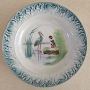 Plat de service terre de fer à décor d'enfant et cigogne