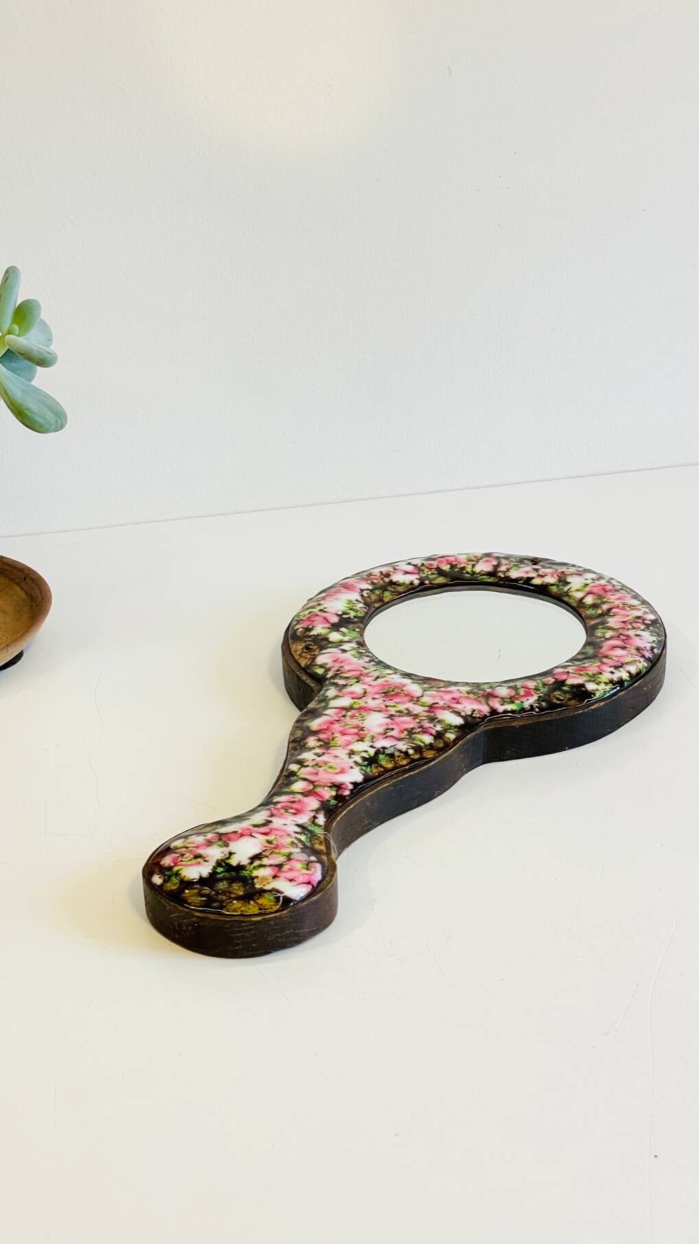 Vintage enameled metal hand mirror on wood