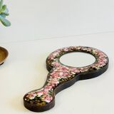 Vintage enameled metal hand mirror on wood