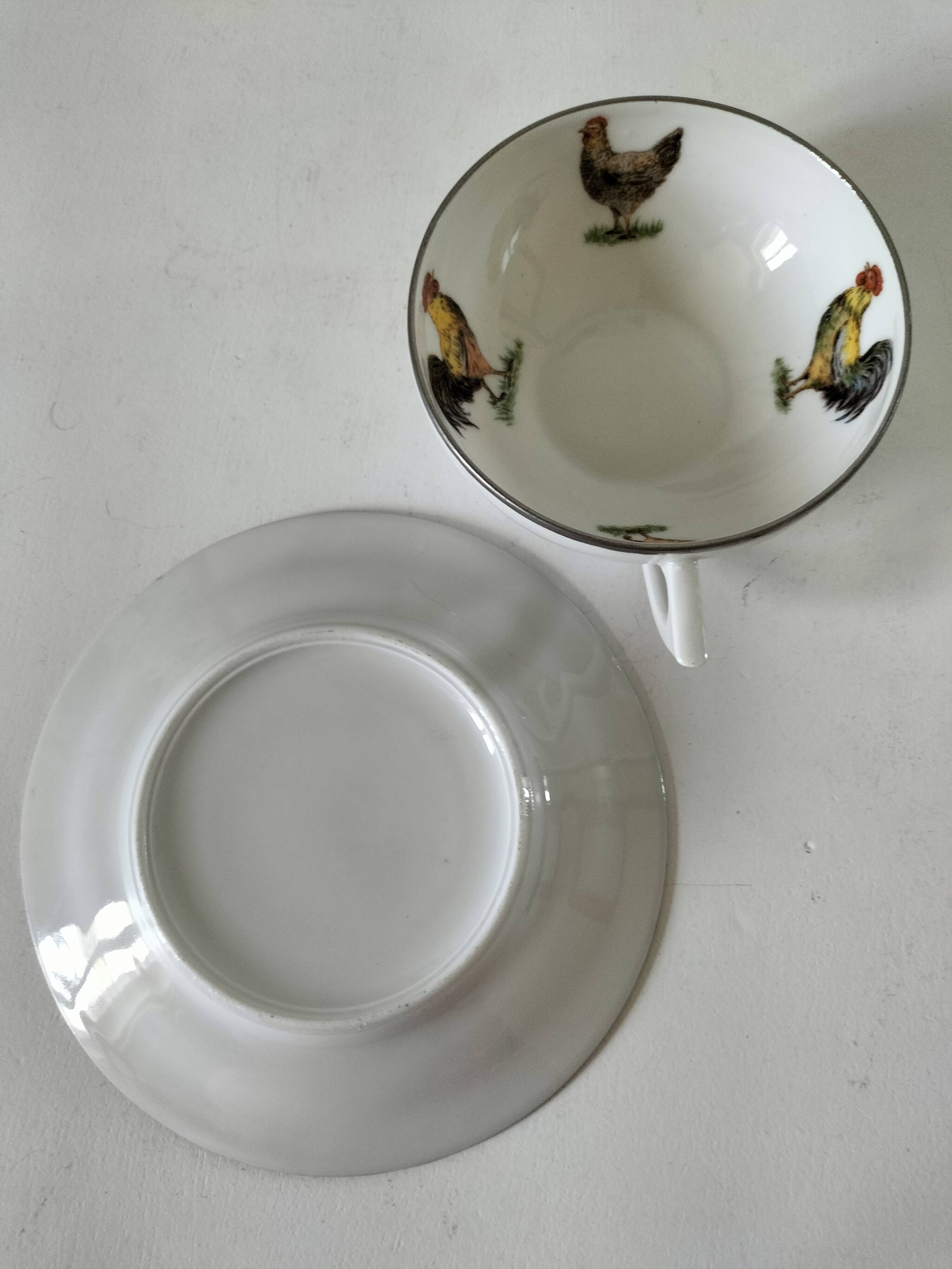 Cup and saucer in porcelain decorated with roosters and hens.