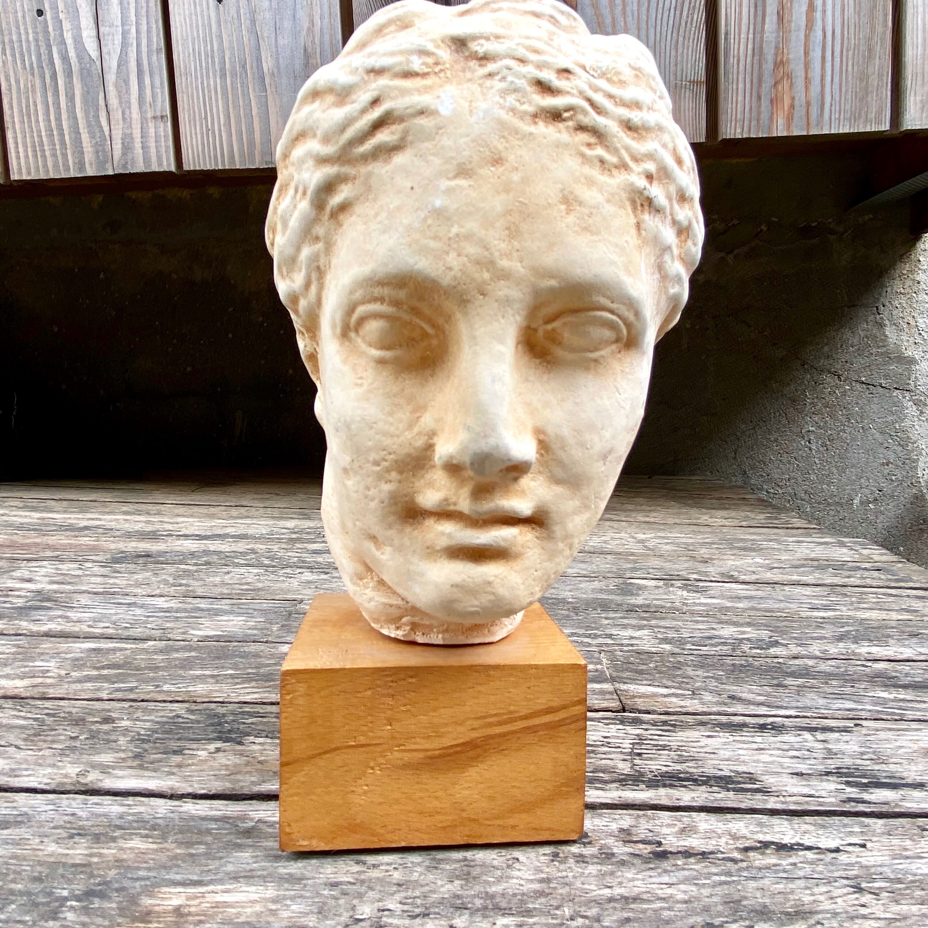 Plaster head of an ancient goddess on its wooden base